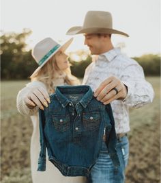 a man and woman holding up a denim shirt