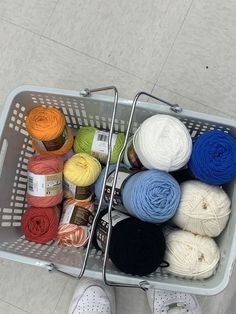 a basket filled with balls of yarn and crochet hooks on top of a floor