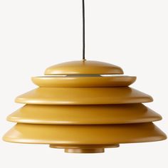 a yellow lamp hanging from a ceiling with a black cord in the middle of it