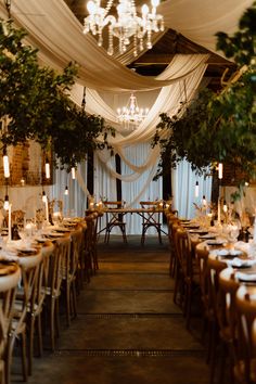 This is showing a barn wedding dining area. The overall vibes are rustic luxury. On the ceiling are glass chandeliers, white drapes hanging across the ceiling, directly above the wooden long dining tables are hanging boards with ivy on them. On the tables are white table runners, vases, candlesticks, tableware and glassware. In the middle of the two rows of dining tables is a sweet heart table at the end. Wedding Ceiling Drapery, Curtain Ceiling Design, Wedding Drapes Ceiling, Black Draping Wedding, Wedding Decor Draping, Wedding Ceiling Draping, Digital Daydream, Wedding Table Layout