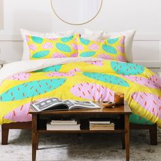 a bed with yellow and pink bedspread in a bedroom next to a coffee table