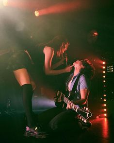 two women on stage with one holding a guitar