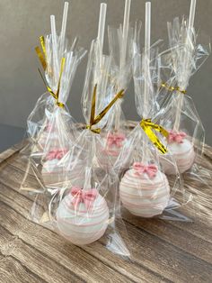 some pink and white cupcakes wrapped in cellophane on a wooden table