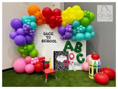 there are many balloons and toys on the floor in front of this school sign that says back to school