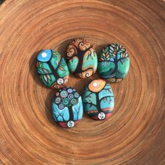 four painted rocks sitting on top of a wooden table