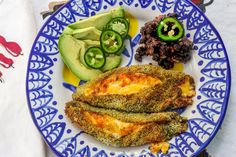 a blue and white plate topped with food next to cucumber, lettuce and tomatoes