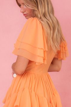 The Solana Dress in Apricot is a stunning piece that will elevate any wardrobe. Its unique features, including a square neckline, flutter sleeves, & a ruffle tiered skirt with pockets, make it both fashionable and functional. The hidden back zipper and functional front corset add a touch of elegance. With a non-stretch fabric and a lined bodice and skirt, this dress offers both comfort and style. Fitted Ruffle Dress With Flutter Sleeves, Summer Ruched Ruffle Sleeve Dress, Summer Ruched Dress With Flutter Sleeves, Summer Dress With Ruffled Skirt And Flutter Sleeves, Summer Ruffle Dress With Ruched Sleeves, Summer Dresses With Ruffles And Flutter Sleeves, Summer Ruffle Sleeve Dress With Ruched Details, Fitted Flutter Sleeve Ruffle Dress, Fitted Flutter Sleeve Dress With Ruffles