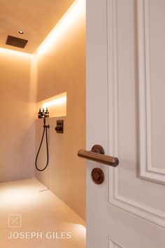 an open door leading to a bathroom with a shower head on the wall next to it