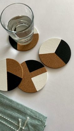 three coasters sitting on top of a white table next to a glass of water