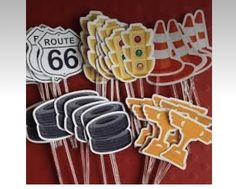 a bunch of cookies that are shaped like road signs and cars on sticks in front of a red background