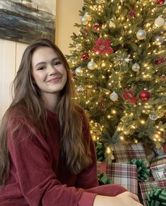 a woman sitting in front of a christmas tree