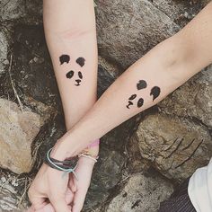 two people are holding hands with tattoos on their arms that look like pandas faces