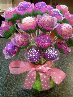 a vase filled with pink and purple candy covered in polka dot wrappers on top of a table