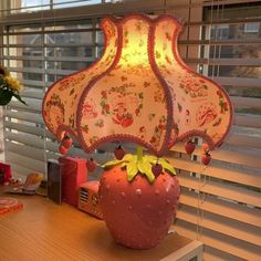 a lamp sitting on top of a wooden desk in front of a window with blinds