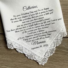 a white handkerchief with an embroidered poem on the front and back, sitting on a wooden surface