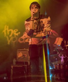 a man standing on top of a stage holding a microphone