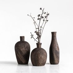 three vases with flowers in them on a white surface