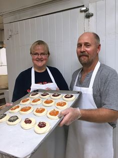 two people holding a tray with pastries on it