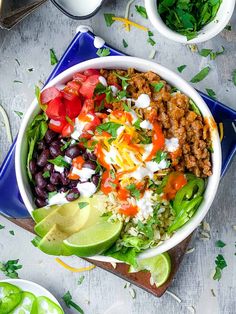 a large bowl filled with taco salad on top of a blue plate next to other bowls