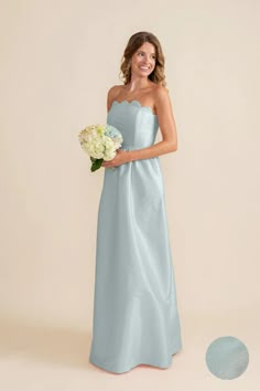 a woman in a blue bridesmaid dress standing next to a white flower bouquet