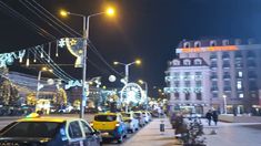 cars are parked on the street in front of buildings and christmas lights hanging from wires