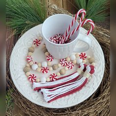 a white plate topped with candy canes next to a cup filled with marshmallows