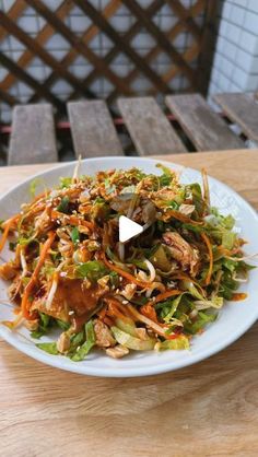 a white plate topped with salad on top of a wooden table