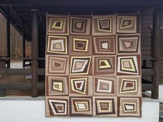 a quilt hanging on the side of a building with brown and yellow squares in it