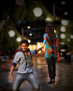 a man holding the hand of a woman on a street with lights in the background