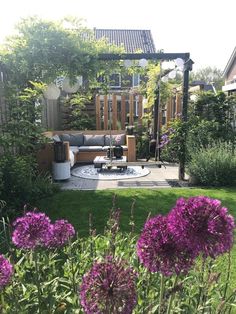 an outdoor living area with purple flowers in the foreground