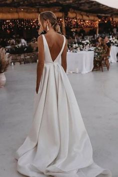 a woman in a white wedding dress standing on the dance floor with her back to the camera