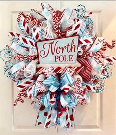 a wreath with the words north pole on it and candy canes hanging from the front door