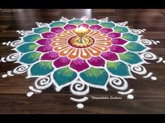 a colorful flower design is on the floor with candles in front of it and an open candle