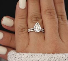 a woman's hand with two wedding rings on it and a white manicure