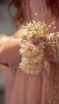 a woman in a pink dress holding a bouquet of white and pink carnations