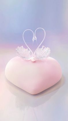 a pink heart shaped pillow with wings on it