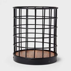 a black wire basket with wood in the bottom and inside it, on a white background