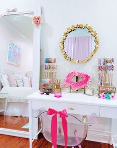 a white desk topped with a mirror and lots of pink decorations on top of it