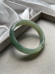 Item Code: JBG223012 Grade 'A' Burmese Jadeite Bangle Jadeite enthusiasts will love this piece of jade bangle. This bangle not only have achieved jelly like texture but, it is so fine that the clarity and translucency is very good. This jade bangle also has the green marbling at some parts of it. One of the most interesting things about this jade bangle is the crystal like structure of this bangle is really fine, the surface is somehow as if it is being dusted with fine glitter dust albeit not being captured in the photos. This piece has no flaws and only perfection can be seen. This piece will be sent to our local Singapore Gem Laboratory to obtain local certification upon purchasing. No extra charges required. Measurement: Inner Diameter: 56.8mm Width: 13.7mm Thickness: 6.6mm Photography Cheap Green Bangle For Women, Jade Stone Bracelet, Unique Luxury Jade Jewelry, Cheap Green Metal Bangle, Jade Bracelet Meaning, Jade Jewelry Aesthetic, Minimalistic Jewelry Aesthetic, Jade Bangle Aesthetic, Elegant Jade Round Bangle