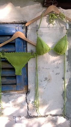 two bikinis are hanging on the wall next to each other with green string attached to them