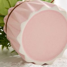 a pink and white plate sitting on top of a table next to some green leaves