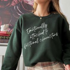 "Emotionally Attached to Fictional Characters" sweatshirt. This cozy crewneck makes a great gift for any book lover! This unisex heavy blend crewneck sweatshirt is pure comfort. These garments are made from polyester and cotton. This combination helps designs come out looking fresh and beautiful. The collar is ribbed knit, so it retains its shape even after washing. There are no itchy side seams on these sweaters.  -50% Cotton 50% Polyester\n.:  -Medium-heavy fabric  -Loose fit -Sewn in label -R Bookish Clothes, Relaxed Fit Bookish Sweatshirt For Fall, Cute Book Sweatshirts, Bookish Crewneck, Emotionally Attached To Fictional Characters, Literary Sweatshirt, Reading Sweatshirt