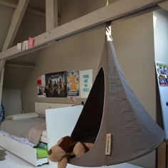 a teddy bear is sitting in a hammock hanging from the ceiling above a bed