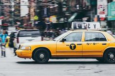 a yellow taxi cab driving down a street next to tall buildings