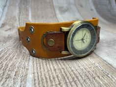 Here's a wide yellow and brown handcrafted steampunk watch.  It is 1-1/2 inches wide and will fit medium to large wrists from 7.0 to 8-3/4 inches around.  Runs on battery. The body of the watchband was hand dyed mustard yellow, and the tabs were hand dyed brown.  The watch band is tapered so your wrist can bend freely.   Antique Brass colored gears, grommets, rivets, and buckle. We also have wide band watches for smaller wrists and narrow width watches in both small and large sizes. Back to shop:  https://www.etsy.com/shop/MonardaZ?ref=hdr-shop-menu Vintage Adjustable Cuff Watch, Adjustable Steampunk Brown Watch, Vintage Cuff Watch, Adjustable Brown Steampunk Watch Accessories, Vintage Handmade Adjustable Watch Accessories, Vintage Cuff Watch Band As Gift, Handmade Adjustable Brown Watch, Handmade Brown Adjustable Watch, Vintage Brown Adjustable Watch Band