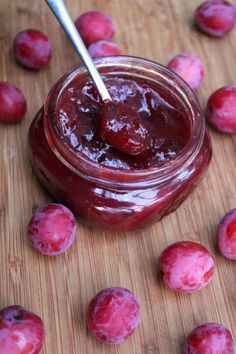 a jar filled with jelly sitting on top of a wooden cutting board next to small pieces of fruit