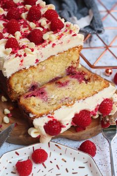 a cake with white frosting and raspberry toppings on a cutting board