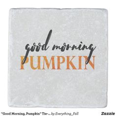 the words good morning pumpkin are painted on a white stone coaster with orange and black lettering