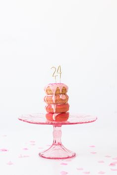 a pink cake sitting on top of a glass plate covered in frosted donuts