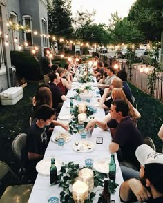 a group of people sitting at a long table with plates and drinks in front of them